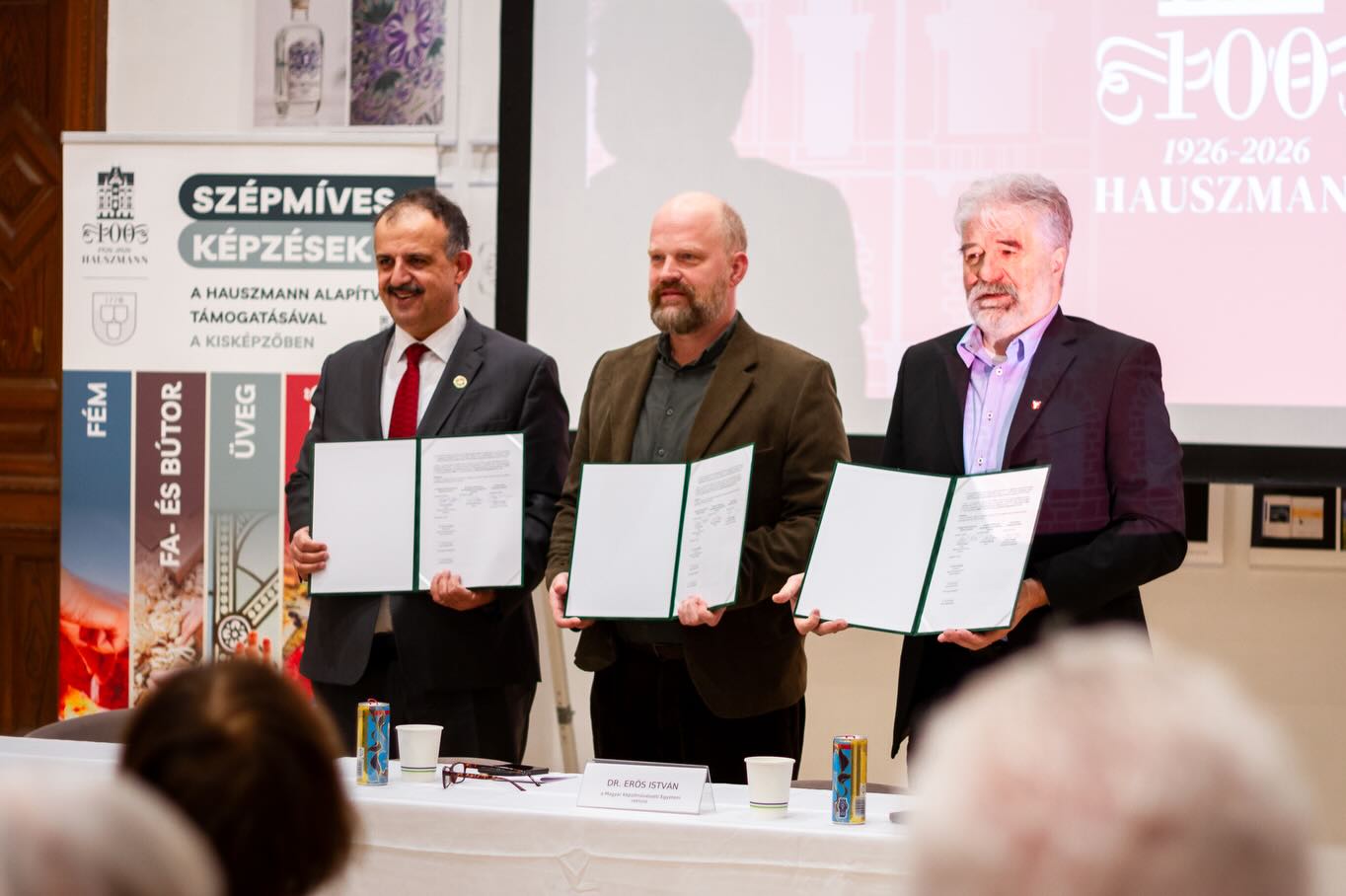 Mesterek képzése – oktatási szimpózium és egyetemközi együttműködés
2026. március 19-én a Magyar Képzőművészeti Egyetem és a Hauszmann Alapítvány „Mesterek képzése” címmel oktatási szimpóziumot rendezett.
A rendezvény a Hauszmann Alapítvány támogatásával megvalósuló, a Képző- és Iparművészeti Szakgimnáziumban zajló szépmíves mesterségek oktatásának tartalmi és módszertani kérdéseit járta körül. A program három szekcióban, kilenc előadás és két workshop keretében adott átfogó képet a képzés jelenéről és jövőjéről.
A szimpózium egyben a Hauszmann 100 Emlékév nyitóeseménye is volt.
A centenáriumi év együttműködő intézményeinek képviseletében Fodor Gergely, Dr. Erős István és Dr. Charaf Hassan köszöntőiket követően ünnepélyes keretek között írták alá az együttműködési nyilatkozatot.
Fotó: @kepkocka